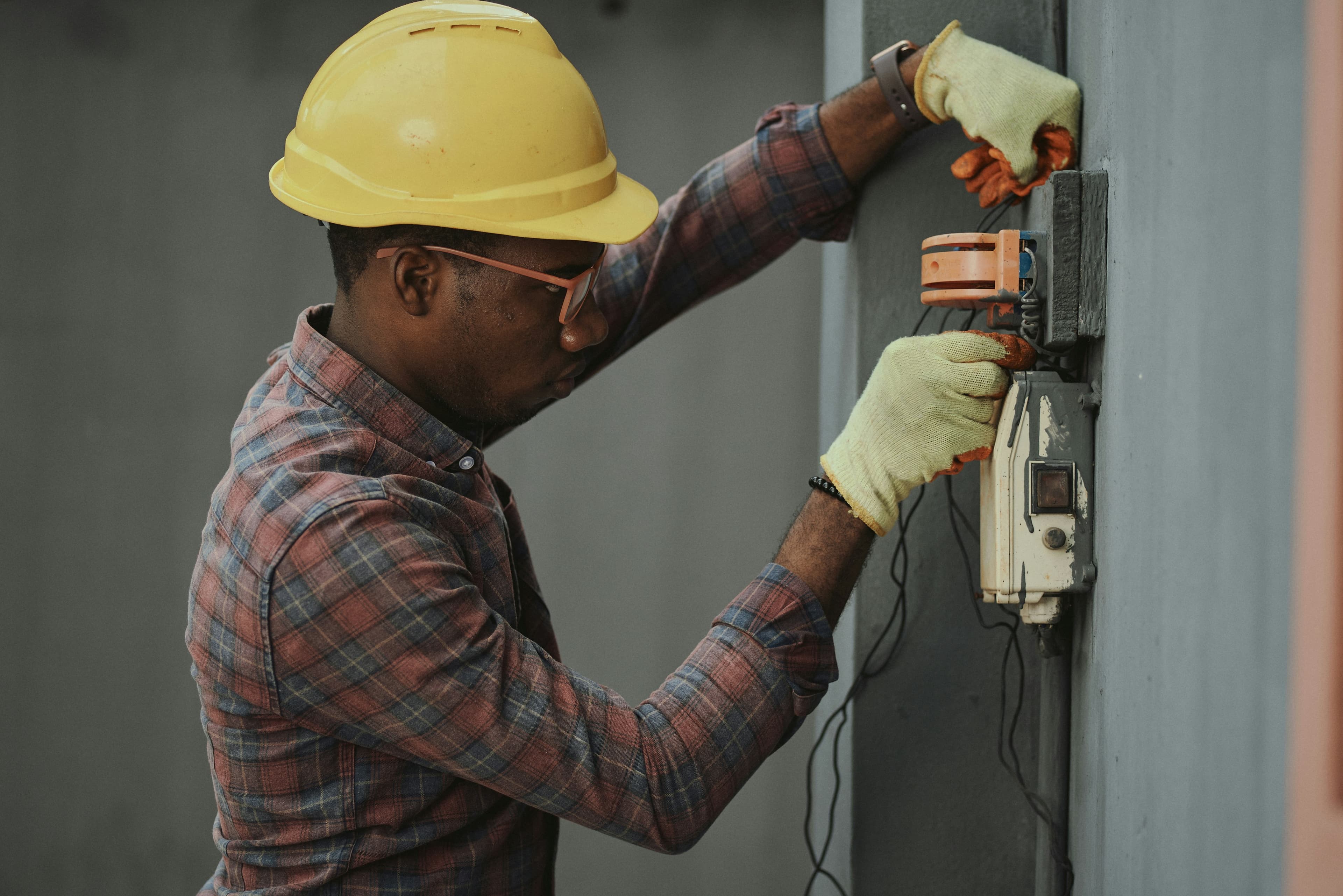 Technician working on a wall-mounted utility connection box